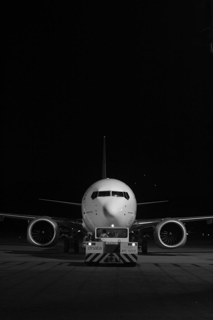 Black and white photo of a commercial airliner on runway at night, front view.